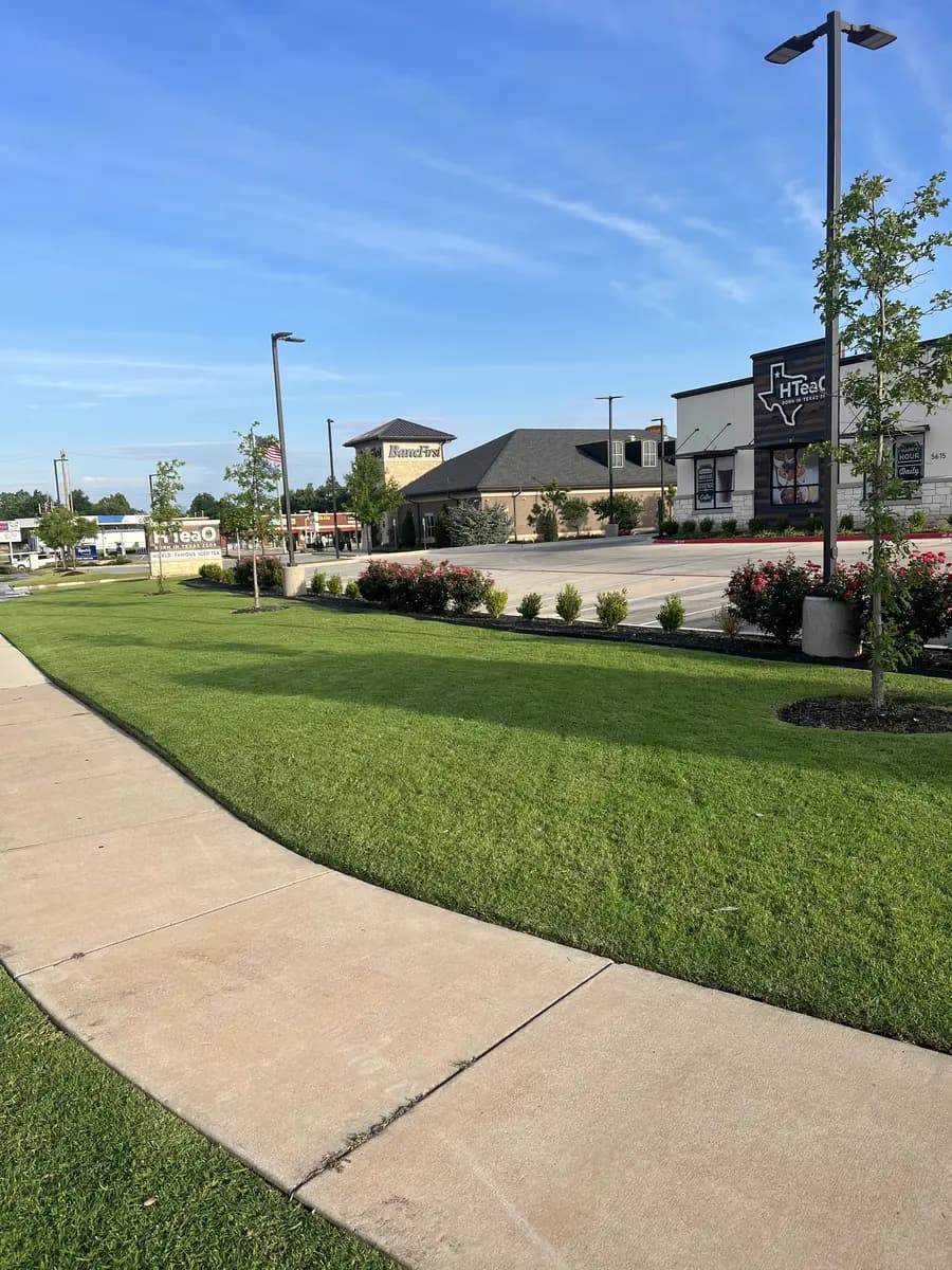 Trimmed commercial lawn and landscaped beds along the HTeaO property