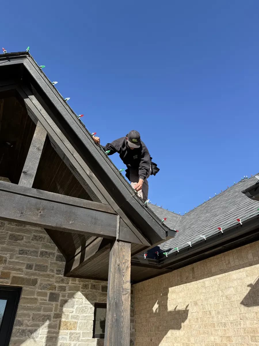 Greenline technician installing Christmas lights on a residential roofline