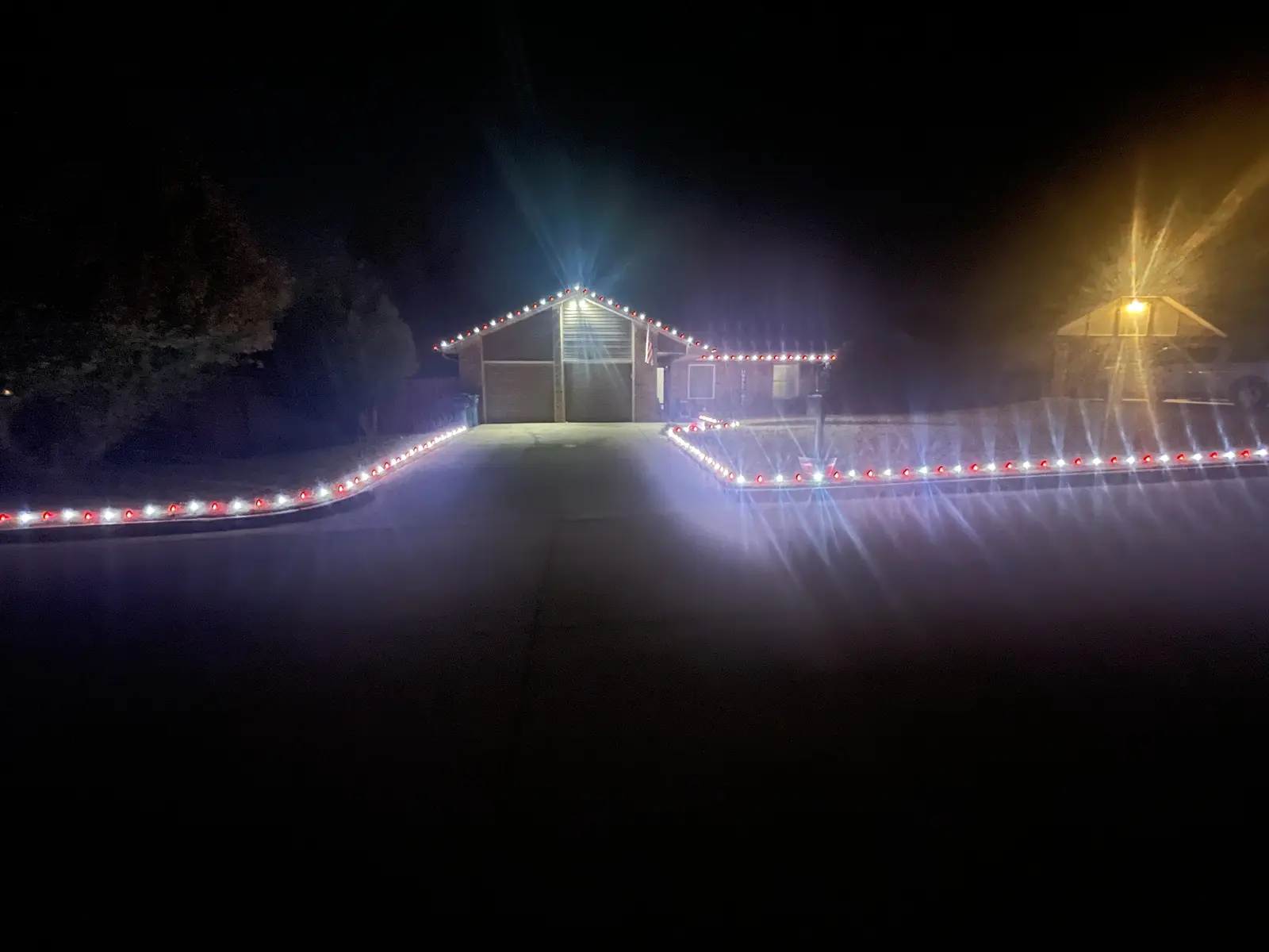 Red-and-white Christmas lights tracing the roofline, driveway, and front-yard border of a residential home