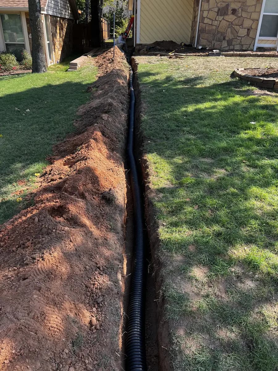 Black corrugated drain pipe installed in a trench through a residential side yard