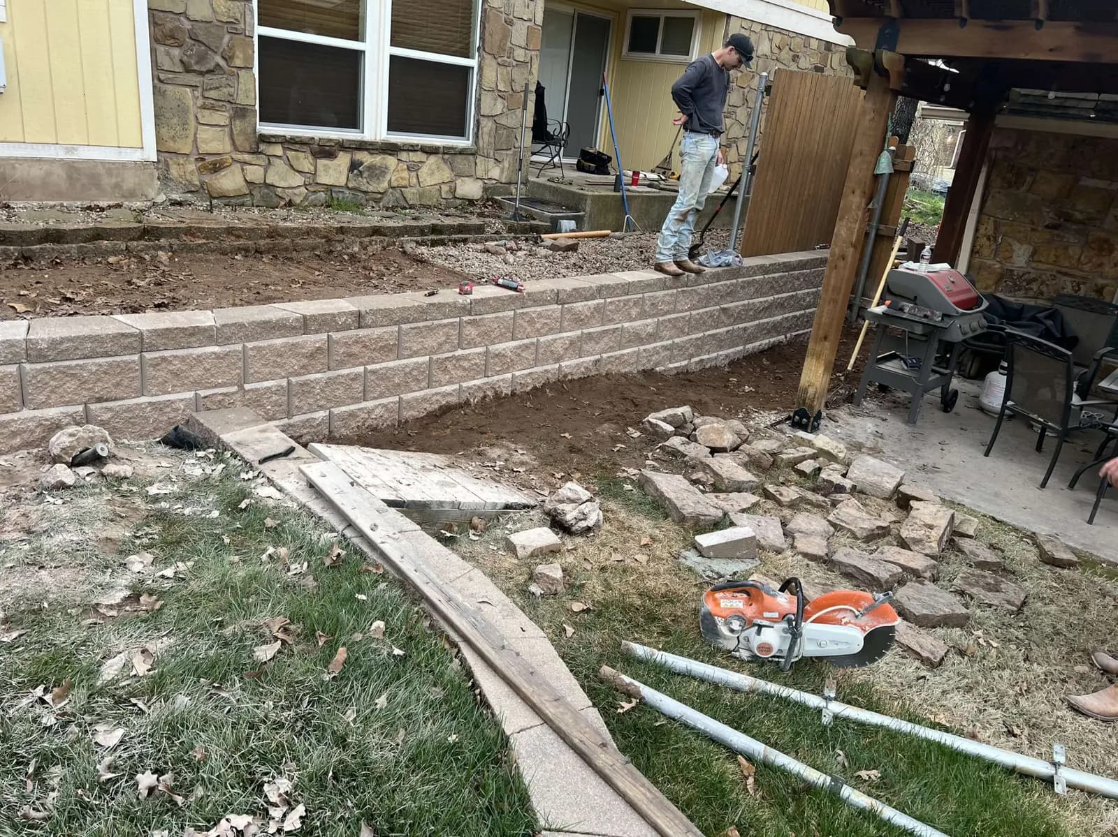 Greenline crew building a segmental block retaining wall behind a residential patio