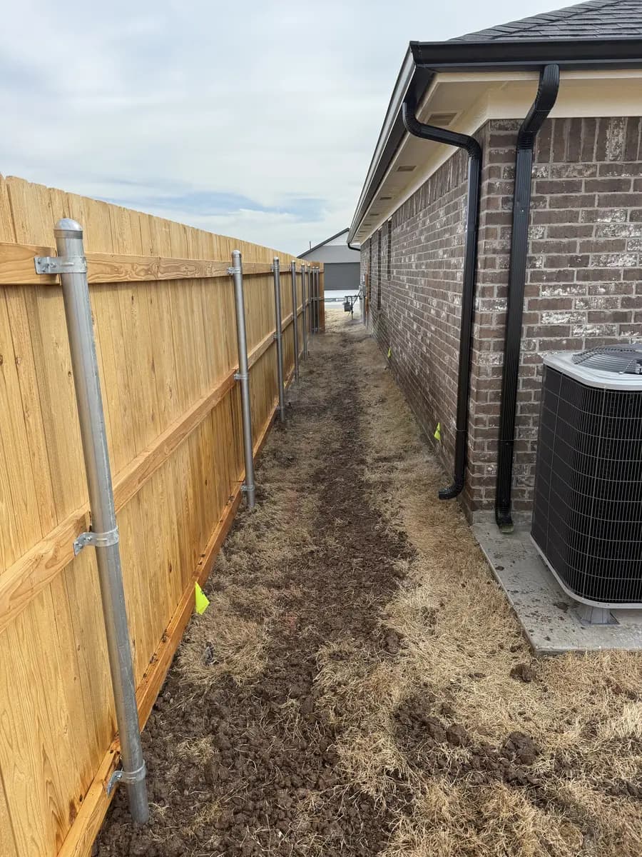 Side-yard turf area prepared for restoration beside a new fence